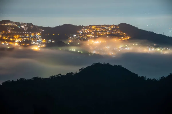 Clouds moving in the sky at night. Neon lights shine on the vibrant cityscape. Hazy and dreamy city night view. Lion\'s Head Mountain, New Taipei City, Taiwan