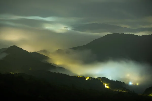 Clouds moving in the sky at night. Neon lights shine on the vibrant cityscape. Hazy and dreamy city night view. Wufen Mountain, New Taipei City, Taiwan