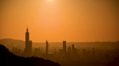 Alacakaranlıkta Taipei şehrinin silueti. Güneş ufka doğru ilerliyor. İklim değişikliğine ve endüstriyel gelişime dikkat edin. Tayvan