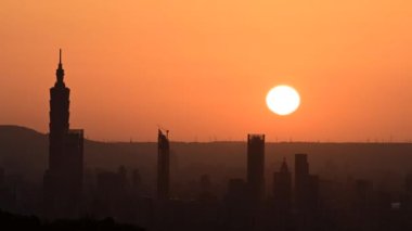 Alacakaranlıkta Taipei şehrinin silueti. Güneş ufka doğru ilerliyor. İklim değişikliğine ve endüstriyel gelişime dikkat edin. Tayvan