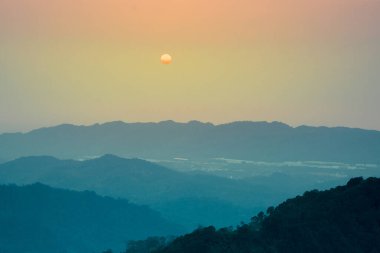 Güneş alacakaranlıkta, dağların üzerinden yüksekten hareket eder. Hakka tarzı dağ manzarası, Dahu Kasabası, Miaoli Bölgesi. Tayvan