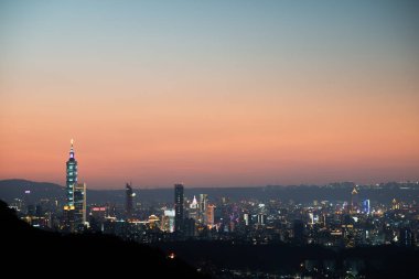 Alacakaranlıkta Taipei şehrinin silueti. Güneş ufka doğru ilerliyor. İklim değişikliğine ve endüstriyel gelişime dikkat edin. Tayvan