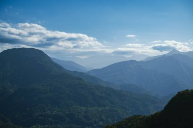 Yeşil dağın üstünde beyaz bulutlar ve mavi gökyüzü. Zihnimi tazeliyor. İklim değişikliğine ve endüstriyel gelişime dikkat edin. Tayvan