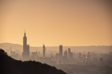 Alacakaranlıkta Taipei şehrinin silueti. Güneş ufka doğru ilerliyor. İklim değişikliğine ve endüstriyel gelişime dikkat edin. Tayvan