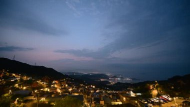 Göz kamaştırıcı alacakaranlık manzarası - canlı turuncu gökyüzü, dinamik bulutlar, sisli dağlar. Tayvan 'ın Jiufen kıyı köyünü çevreleyen Serene Okyanusu.