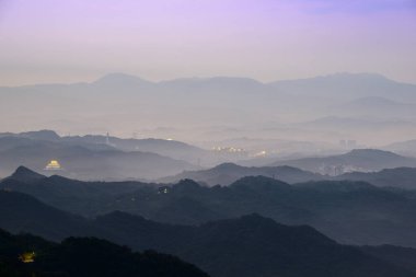 Göz kamaştırıcı alacakaranlık manzarası - canlı beyaz gökyüzü, dinamik bulutlar, sisli dağlar. Tayvan 'ın Jiufen kıyı köyünü çevreleyen Serene Okyanusu.