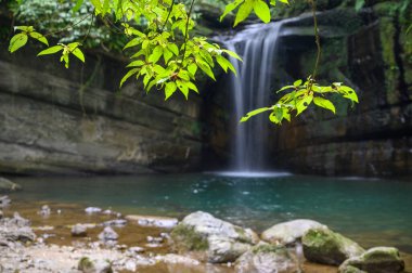 Yosunlu kayaların ve yeşil ağaçların arkasında Wanggu Şelalesi var. Dağ ormanı gizli yeri, göl rüya gibi zümrüt yeşili. Pingxi, New Taipei Şehri.
