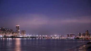 Bulutlar gece şehrinde hareket eder. Nehir suyuna renkli ışıklar yansıtılır. Tarihi manzaralar ve ünlü turistik yerler. Dadaocheng Rıhtımı, Taipei, Tayvan