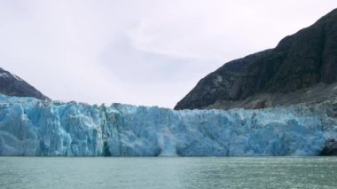Muhteşem bir buzul yavrusu. Buz küpleri bir patlama gibi suya düştü. Mavi bir nehre dökülen kayıktan görünen buzdan bir duvar. Alaska 'da yaz.