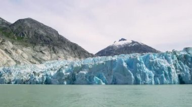 Muhteşem bir buzul yavrusu. Buz küpleri bir patlama gibi suya düştü. Mavi bir nehre dökülen kayıktan görünen buzdan bir duvar. Alaska 'da yaz.