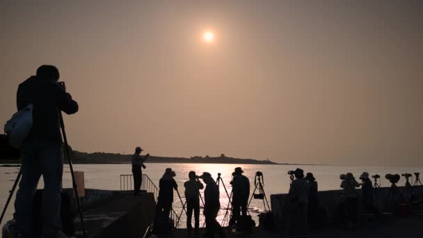 夕暮れ時に海によって多くの写真家のシルエット 夕日の撮影や観光地として知られる福井岬灯台 — ストック動画