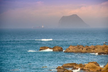 Sis, mavi deniz ve mavi gökyüzü ile kaplanmış küçük bir ada. New Taipei 'deki Wanli Sahili' nden Keelung Adası manzarası. Tayvan.