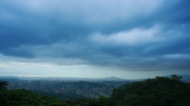 Kara bulutlar hızla hareket ediyor. Alacakaranlıkta, bulutlu bir günde Taipei şehrinin manzarası.