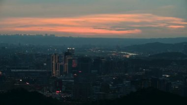 Gün batımı parıltısı, araba ışıkları ve neon ışıkları gecenin geldiğini bildirir. Şehir manzarasına ve Xizhi, New Taipei 'den Keelung Nehri' ne bakıyor..