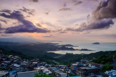 Dağlar ve denizlerle çevrili bir köy. Mavi gökyüzü ve renkli dinamik bulutlar. Alacakaranlıkta Jiufen. Ruifang Bölgesi, New Taipei Şehri, Tayvan