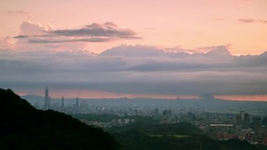 Akşam dağlarda parlıyor. Şehrin üzerinde dramatik dinamik kara bulutlar. Dajianshan Dağı 'ndan kentsel manzara, Yeni Taipei Şehri, Tayvan