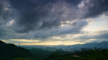 Akşam dağlarda parlıyor. Şehrin üzerinde dramatik dinamik kara bulutlar. Dajianshan Dağı 'ndan kentsel manzara, Yeni Taipei Şehri, Tayvan