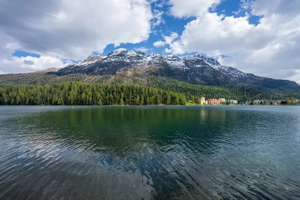 Snow-covered mountains, clear lakes, lakeside houses and coniferous forests. St. Moritz Retreat: Capturing the Scenic Landscapes of a Swiss Vacation Town.