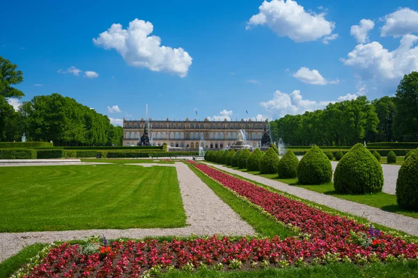 Yaz bahçesi manzarası. Mavi gökyüzü ve beyaz bulutlar, ağaçlar, çimenler, kırmızı çiçekler. Schloss Herrenchiemsee, Almanya 'da yer alan bir şehirdir..