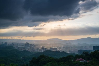 Dinamik Crepuscular Ray ve Guanyin Dağı 'nın silueti. Dajianshan Dağı, New Taipei Şehri 'nden şehir manzarası.