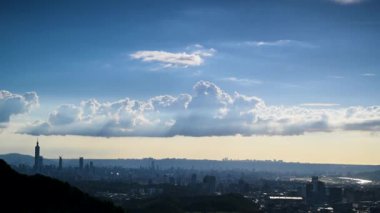Gün batımında şehrin üzerinde beyaz dinamik bulutlarla mavi gökyüzü. Dajianshan Dağı 'ndan kentsel manzara, Yeni Taipei Şehri, Tayvan
