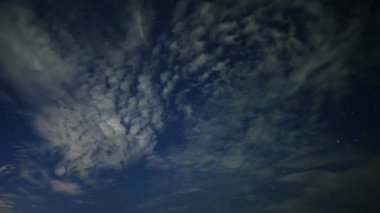 Gece mavisi gökyüzü, dans eden beyaz bulutlar ve parıldayan yıldızlar. Yazın New Taipei 'deki Timsah Adası' nda yıldızlı gökyüzü.