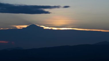 Batan güneş bulutlar tarafından gizleniyor. Değişen dinamikleri olan kara bulutlar. Wufenshan Hava Radar İstasyonu dağın tepesinde duruyor. Tayvan