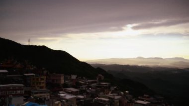 Göz kamaştırıcı alacakaranlık manzarası - canlı turuncu gökyüzü, dinamik bulutlar, sisli dağlar. Tayvan 'ın Jiufen kıyı köyünü çevreleyen Serene Okyanusu.