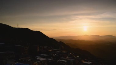 Göz kamaştırıcı alacakaranlık manzarası - canlı turuncu gökyüzü, dinamik bulutlar, sisli dağlar. Tayvan 'ın Jiufen kıyı köyünü çevreleyen Serene Okyanusu.