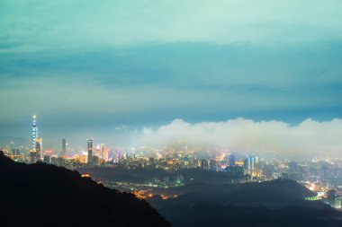 Şehir ışıkları ve değişen bulutlar: bir dağın tepesinden izlenen bir manzara. Dajianshan Dağı 'ndan kentsel manzara, Yeni Taipei Şehri, Tayvan.