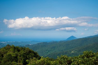 Blue Sky Majesty: Dağdaki Dinamik Beyaz Bulutları Yakalıyorum. Dajianshan Dağı 'ndan kentsel manzara, Yeni Taipei Şehri, Tayvan.