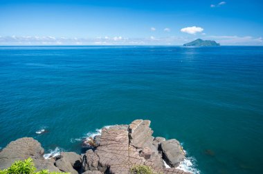 Mavi deniz ve mavi gökyüzü ve değişen beyaz bulutlar. Küçük adalar ve kayalar. Guishan Adası (Kaplumbağa Adası) Pasifik Okyanusu 'nda bir volkanik adadır. Tayvan