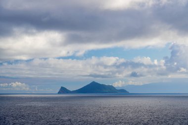 Mavi deniz ve mavi gökyüzü ve değişen beyaz bulutlar. Küçük adalar ve kayalar. Guishan Adası (Kaplumbağa Adası) Pasifik Okyanusu 'nda bir volkanik adadır. Tayvan