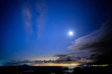 Deniz kıyısında balıkçı teknesi ışıkları, Samanyolu ve gökyüzünde dinamik bulutlar. Guishan Adası (Kaplumbağa Adası) Pasifik Okyanusu 'nda bir volkanik adadır. Tayvan