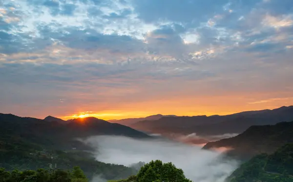 The sun rose at the top of the mountain as the orange-red clouds turned grey. Early morning view of tea gardens, a sea of clouds and sunrise, Nanshan Temple.