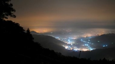 Bulutlarla çevrili bir vadideki aydınlanmış köylerin renkli bir gece görüntüsü. Nantou ilçesindeki Yuchi kasabasındaki Jinlong Dağı 'nın gece manzarası. Tayvan