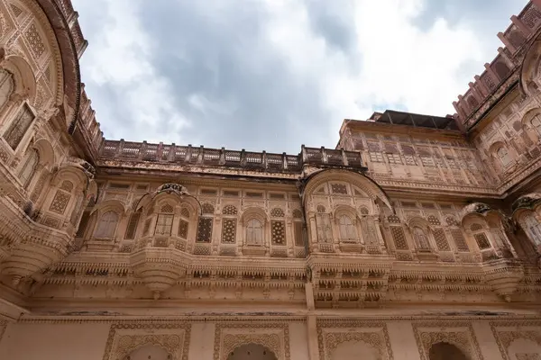 Look up at the red and yellow castle standing majestically on the hill. Mehrangarh Fort is in Jodhpur, Rajasthan, India. UNESCO World Heritage Site.
