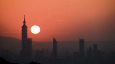 Gün batımında hareketli güneş ve şehir kulesinin birleşik manzarası. Şehir Sıcaklığı: Öğleden Sonra Günışığı ve Sonbaharda Orange City Silueti.