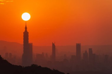 Gün batımında hareketli güneş ve şehir kulesinin birleşik manzarası. Şehir Sıcaklığı: Öğleden Sonra Günışığı ve Sonbaharda Orange City Silueti.