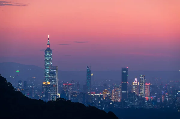 Gradually, colorful lights come on in the evening. Orange-red night view of the city after sunset in autumn. Taipei, Taiwan.
