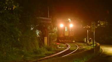 Sarı bir dizel tren geceleri ışıkları açık bir şekilde köyden geçer. Pingxi hattı boyunca nehir vadileri, çukurlar ve şelaleler var. Tayvan