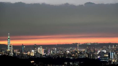Sakin günbatımı tonlarında, Taipei ufuk çizgisinin çarpıcı manzarası ikonik Taipei 101 kulesi tarafından vurgulanır. Xizhi Dajianshan, Tayvan.