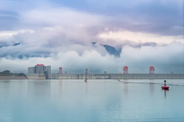 Panoramic view of the Three Gorges Dam, the largest hydroelectric power plant in the world. The sky is blue and clear and the sun is shining brightly.