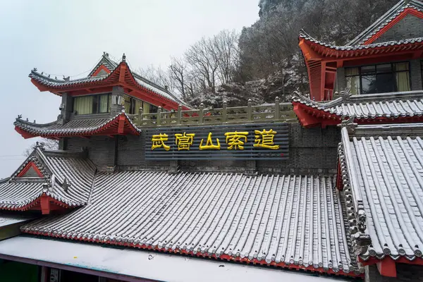 A serene view of the Wudang Mountain cableway station, adorned with traditional Chinese architecture, enveloped in a misty atmosphere.