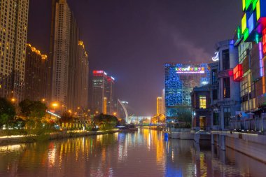 Wuhan, Çin - 21 Mart 2018: Yanxia Köprüsü yakınlarındaki parlak gökdelenler durgun suya güzel bir şekilde yansıdı. Şehrin canlı gece hayatını gösteriyoruz..