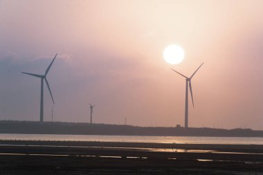Offshore rüzgâr çiftlikleri manzaranın tadını çıkarmak ve gün batımını izlemek için harikadır. Gaomei Windmill Caddesi. Taichung Liman Rüzgarı Güç İstasyonu. Tayvan.