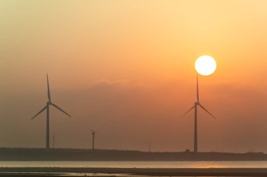 Offshore rüzgâr çiftlikleri manzaranın tadını çıkarmak ve gün batımını izlemek için harikadır. Gaomei Windmill Caddesi. Taichung Liman Rüzgarı Güç İstasyonu. Tayvan.