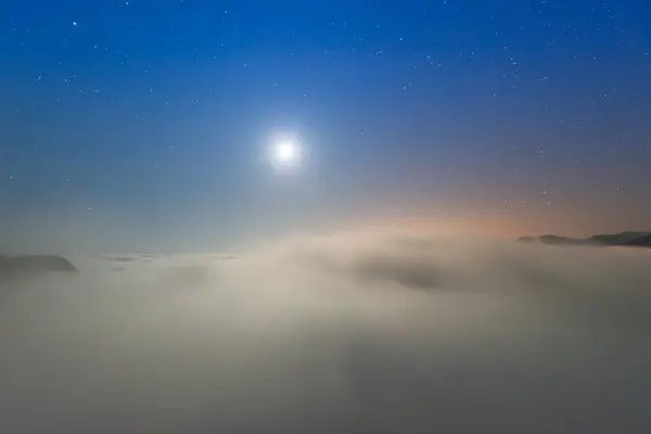 The sea of clouds on a quiet moonlit night makes you feel unpredictable. Peaks surrounding Emerald Reservoir. Xindian District, New Taipei City, Taiwan.
