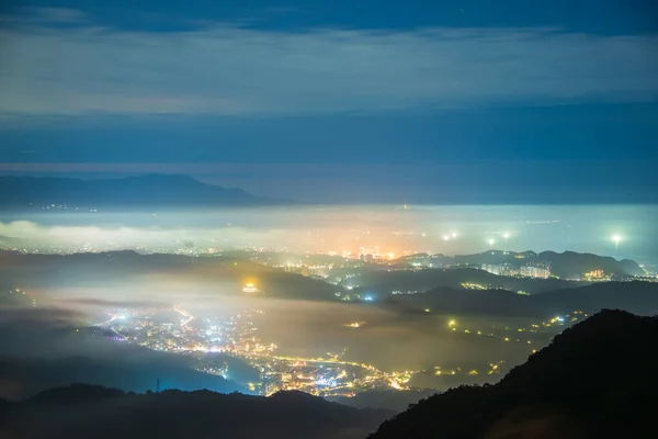 Creating a glazed halo of light from the clouds and the lights of the village. Warm winter mountain scenery in northern Taiwan, Shuangxi Buyanting Pavilion.