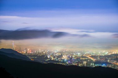 Yuvarlanan bulutlar ve şehir ışıkları gece manzarasını zenginleştiriyor. Dağdan Taipei şehrinin gece manzarasının tadını çıkarın. Tayvan